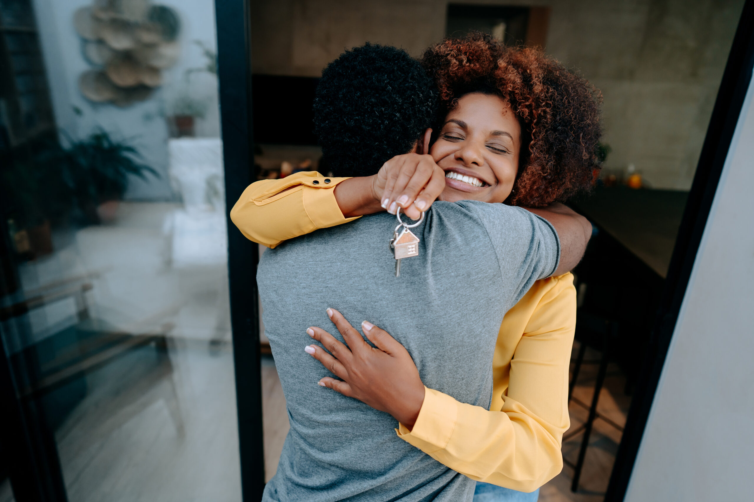 A woman hugging another man while holding keys.